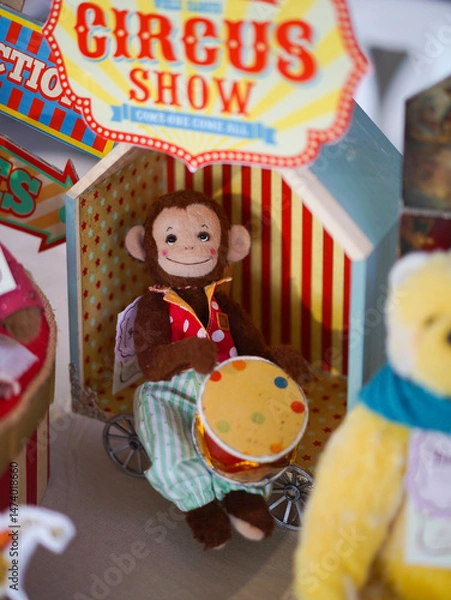 Fototapeta Cute Monkey Doll. A closed up of a happy monkey doll is sitting among his circus friends in colorful circus theme concept. Doll's display during the weekend doll market.