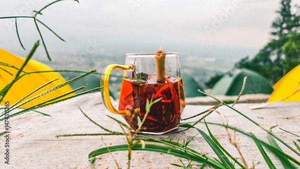Fototapeta Aromatic herbal drink wedang uwuh amidst the serene natural scenery while camping. Made from ginger, sappanwood, cloves, cinnamon, nutmeg leaves, nutmeg, lemongrass, cardamom, and rock sugar