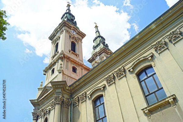 Fototapeta Photographed from the bottom up, the facade of a 19th-century temple with two bell towers and rich decoration in the Baroque and Classical styles. View of the main church in Pancevo, Vojvodina, Serbia