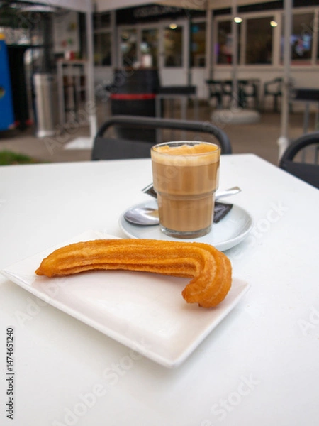 Fototapeta Churros. Fried wheat flour dough, a very popular sweet snack in Spain. at a table on the terrace of a bar-restaurant