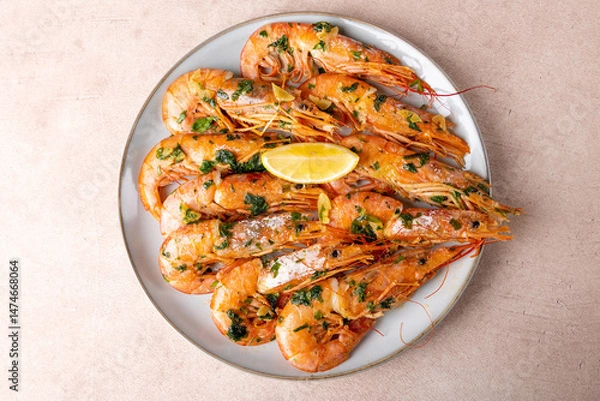 Fototapeta Langoustines fried in butter with garlic and parsley. Served with a slice of lemon. Traditional Mediterranean cuisine. A popular appetizer in restaurants and pubs. Homemade cooking. Selective focus.
