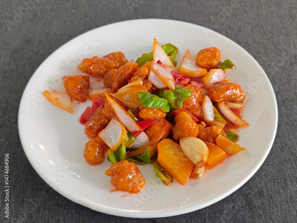 Fototapeta sweet and sour pork with green red peppers and pinapples in the white plate for eating