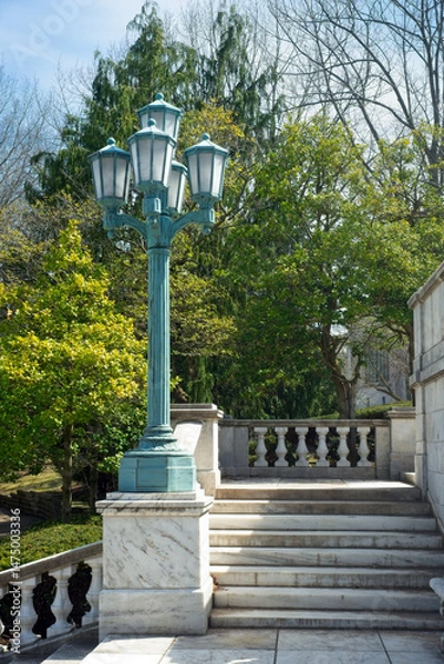Fototapeta A five-lantern lamp post stands on a pedestal above steps to a public park in the University Circle district of Cleveland Ohio.