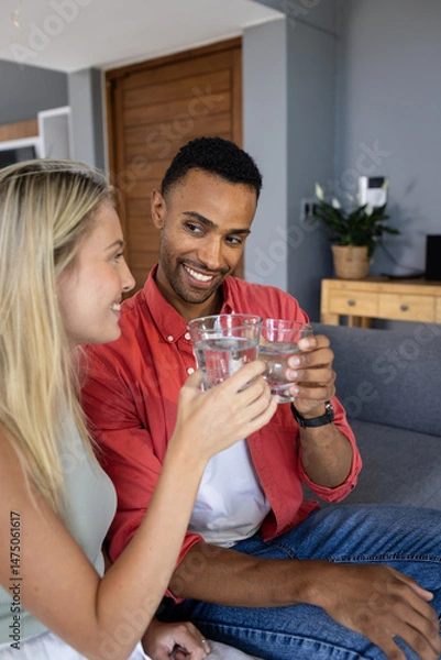 Obraz Couple toasting with glasses of water, smiling and enjoying time together at home