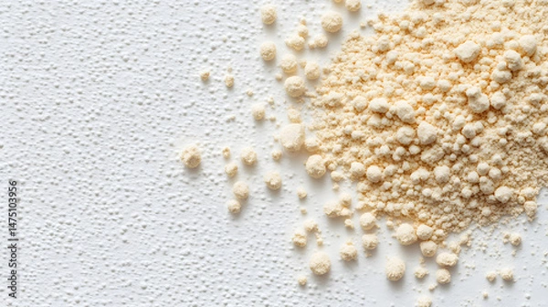 Fototapeta A pile of yellow Asafoetida powder scattered unevenly on a white smooth surface, emphasizing texture and granules.