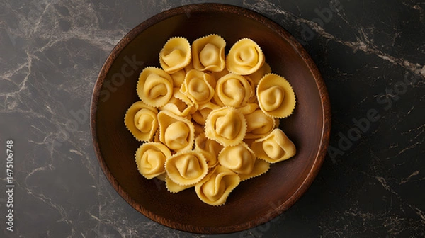 Fototapeta A unique overhead shot of tortellini placed in a circular arrangement, with attention to the details of their texture and the glossy finish of the surface.