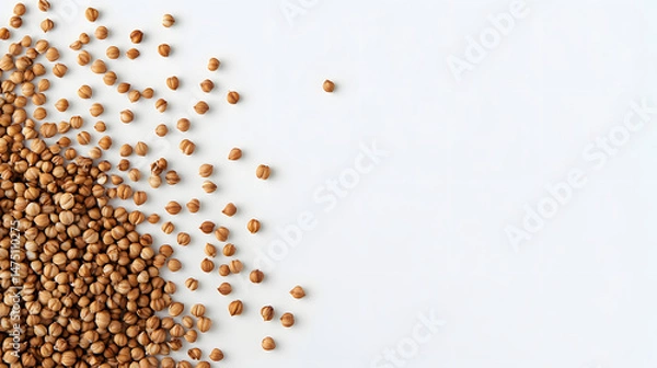 Fototapeta Whole buckwheat grains in brown, scattered on a white background, highlighting their texture and natural appearance.