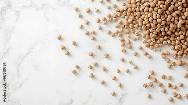 Fototapeta Whole buckwheat grains in light brown, scattered on a white surface, emphasizing their natural shape and texture.