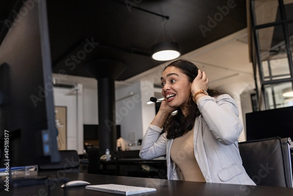 Obraz Businesswoman in office smiling while using headset for video conference call