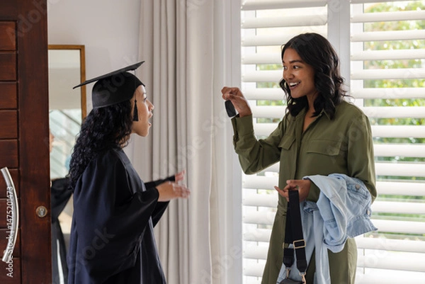 Obraz African American mother surprising daughter with car keys at home on graduation day