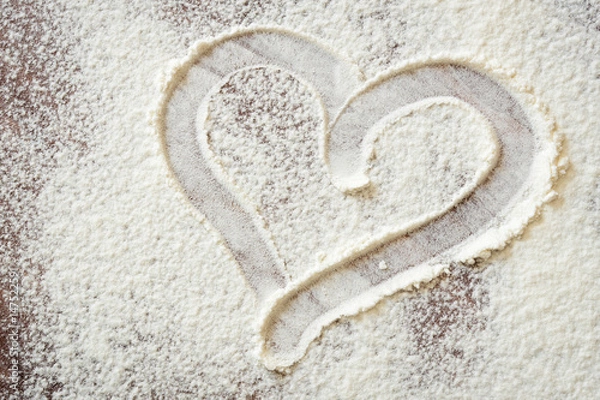 Fototapeta heart drawn with a finger on the Board with flour