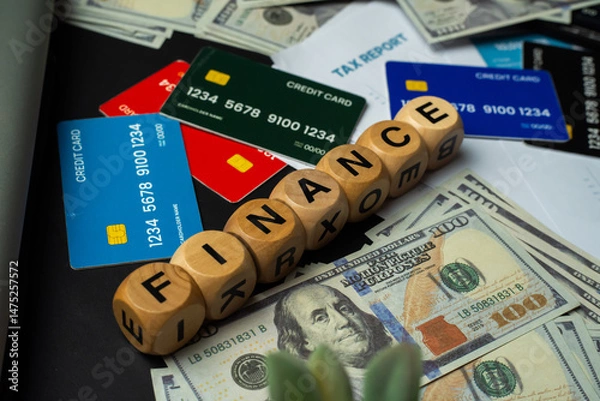 Obraz Conceptual flat lay image symbolizing financial planning and digital payments. Includes realistic mock credit cards, hundred-dollar notes, and wooden cubes arranged to form the word “FINANCE.”
