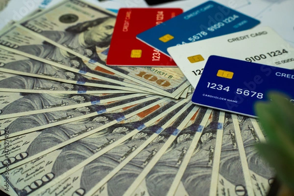 Obraz image showing a spread of hundred-dollar bills beneath multiple colorful credit cards. This visually engaging photo represents modern financial concepts