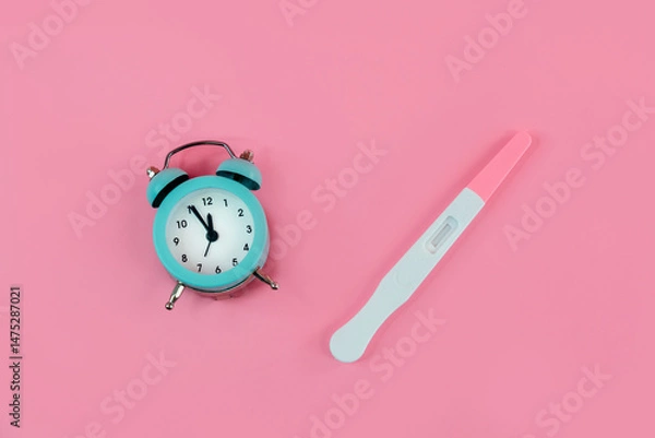 Fototapeta Alarm clock and pregnancy test on pink background, Female fertility biological clock concept, Women's health and fertility
