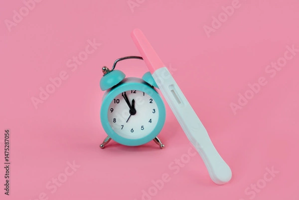 Fototapeta Alarm clock and pregnancy test on pink background, Female fertility biological clock concept, Women's health and fertility