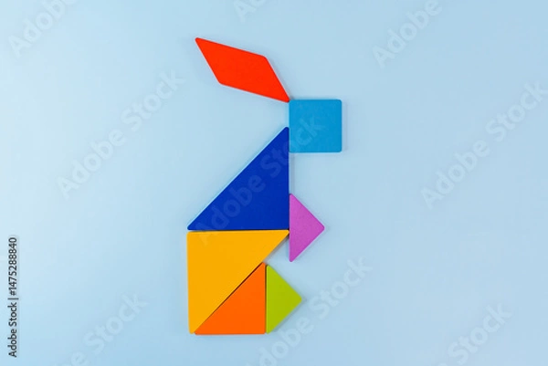 Fototapeta Tangram puzzle depicting a rabbit or a hare on a blue background, conceptual image, place for text