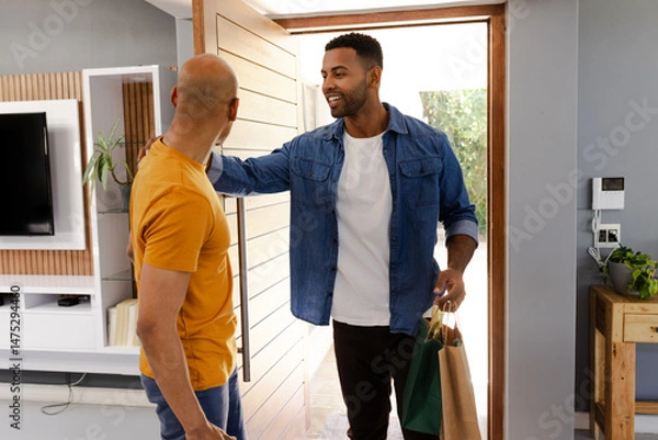 Obraz Friends greeting each other at home, smiling and holding shopping bags