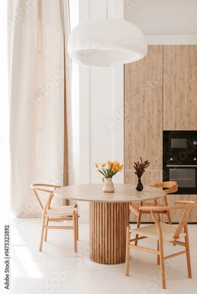 Fototapeta cozy light kitchen with a dining table and chairs