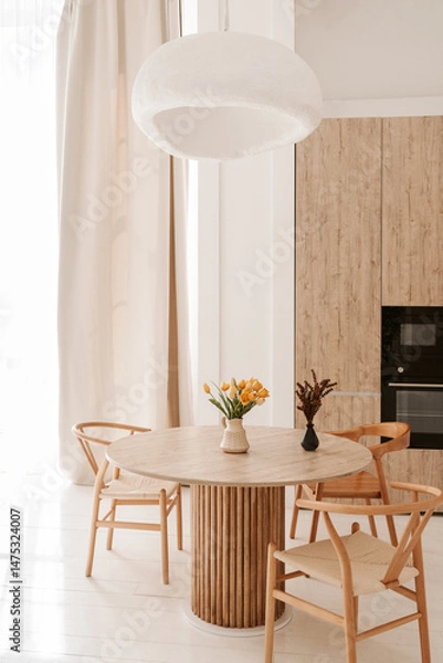 Fototapeta cozy light kitchen with a dining table and chairs