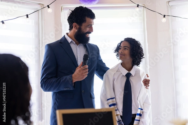Obraz Celebrating son's bar mitzvah, father speaking into microphone at home