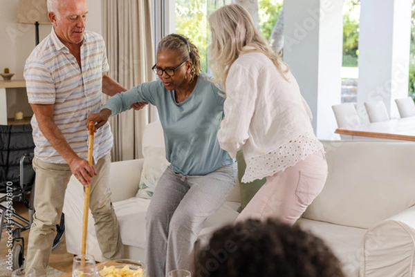 Obraz Senior friends supporting each other at home, helping with mobility and care