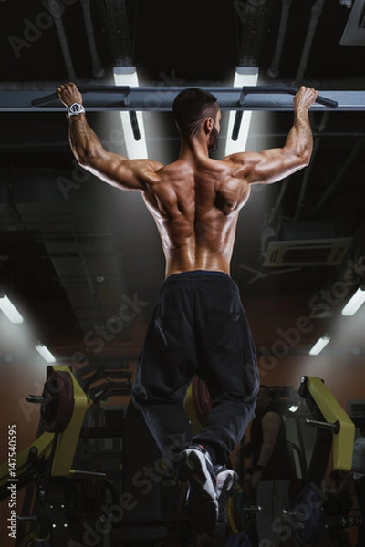 Fototapeta Back view of muscular man doing pull up exercise
