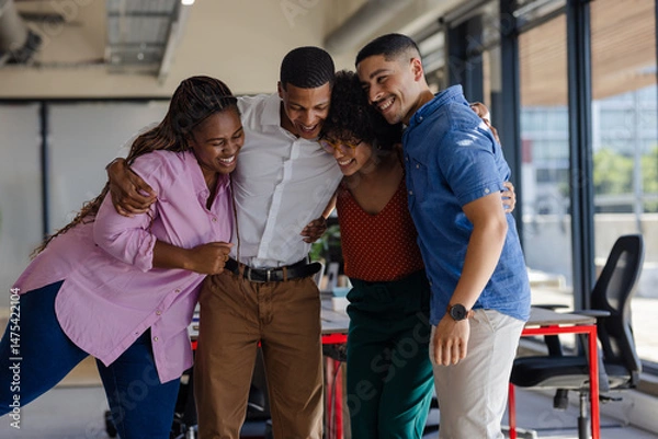 Obraz Diverse colleagues embracing and laughing together in modern office setting