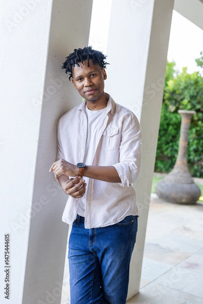 Obraz Smiling man in casual outfit standing outdoors, leaning against pillar