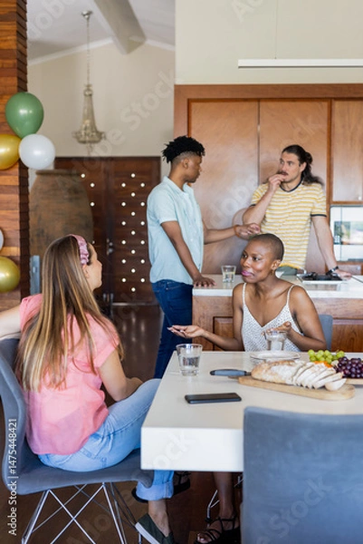 Fototapeta Friends sharing snacks and laughter, enjoying conversation together at home