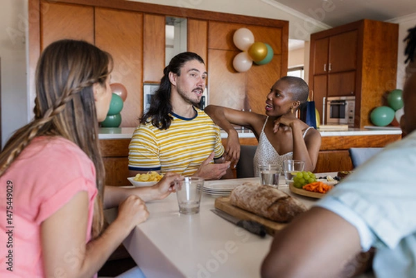 Fototapeta Friends enjoying conversation and snacks at home, sharing laughter and stories