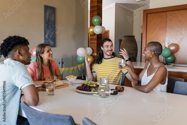 Fototapeta Friends enjoying conversation and snacks at home, sharing laughter and stories