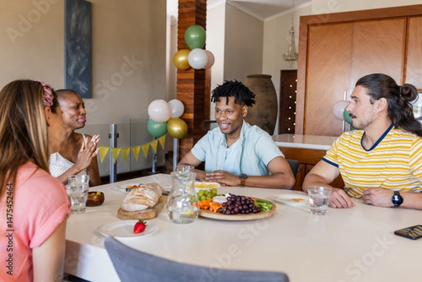 Fototapeta Friends enjoying conversation and sharing snacks at home during casual gathering