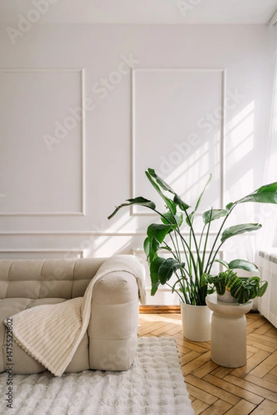 Fototapeta Modern white interior featuring a comfortable couch and elegant greenery