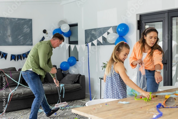 Obraz Family cleaning up after birthday party at home, surrounded by decorations