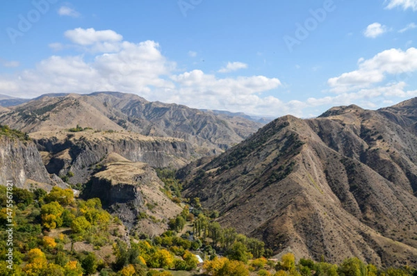 Fototapeta Panoramic view from Garni Temple of a mountainous region featuring rugged terrain, steep slopes, and green valleys under a bright blue sky dotted with clouds, Caucasus, Armenia
