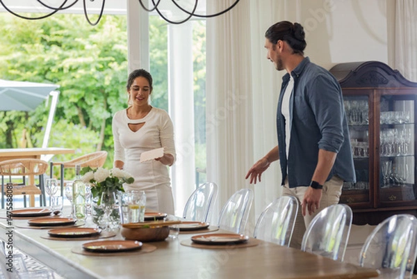 Fototapeta Preparing elegant dining table for wedding, couple smiling and arranging plates