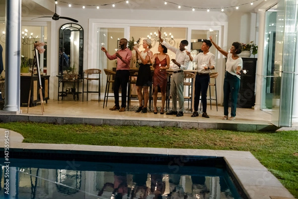 Obraz Friends celebrating with sparklers by poolside at evening wedding reception