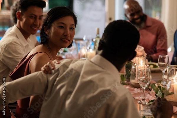 Fototapeta Guests enjoying lively conversation at elegant wedding dinner table with candles