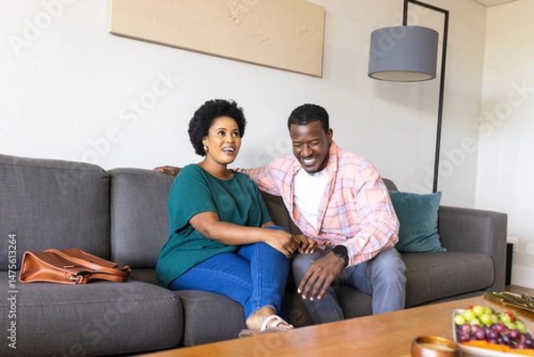 Obraz Laughing together on sofa, friends having casual conversation and relaxing at home