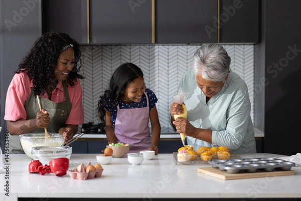 Obraz Three generations baking cupcakes together in modern kitchen, sharing joyful moments