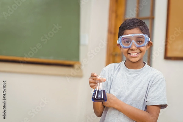 Obraz Conical flask holding dark blue liquid is resting on classroom desk, near green chalkboard