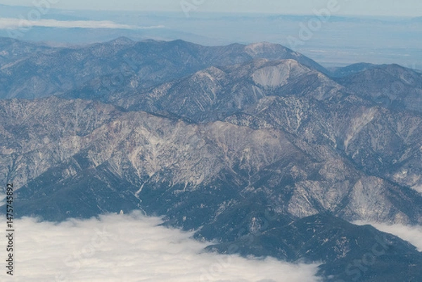 Fototapeta Aerial view of the San Gabriel Mountains outside of Los Angeles featuring Mt Baldy and Mt San Antonio with clouds covering the Pomona Valley