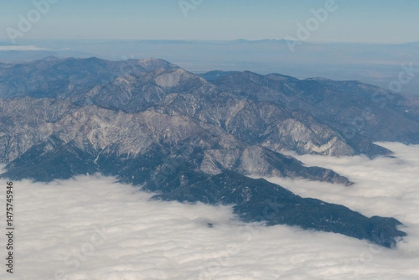 Fototapeta Aerial view of the San Gabriel Mountains outside of Los Angeles featuring Mt Baldy and Mt San Antonio with clouds covering the Pomona Valley