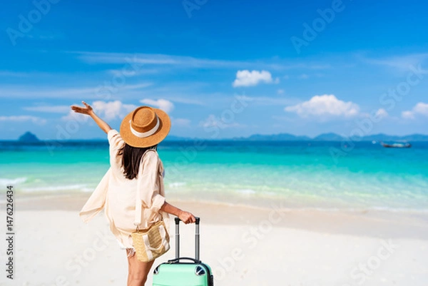 Fototapeta Young woman traveler with luggage relaxing and enjoying at beautiful tropical sand beach, Summer vacation and Travel concept