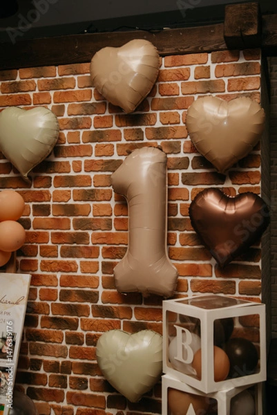 Obraz festive background for celebrating a child's one year or a year of marriage on a red brick background and decorated with colorful balloons and the number one in the center for a photo shoot