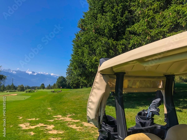 Fototapeta Golf Course with Mountain View and Golf Cart in Crans Montana in Valais, Switzerland.