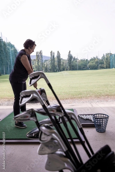 Fototapeta Golfer Practice in Driving Range and a Golf Bag with Golf Clubs in Switzerland.
