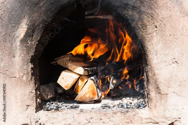 Fototapeta Firewood burns in an ancient stove