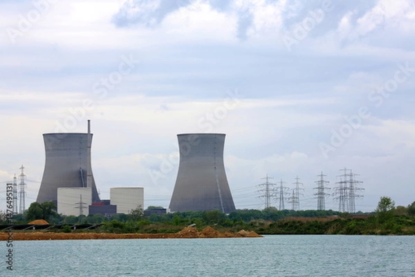 Fototapeta Das Atomkraftwerk Gundremmingen. Die imposanten Kühltürme stehen im Hintergrund und dominieren die Szene mit ihrer markanten hyperbolischen Form. Im Vordergrund erstreckt sich ein Gewässer