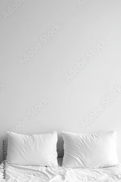 Fototapeta Two white pillows on a bed against a white wall in a minimalist style close up studio shot for sleeping and comfort